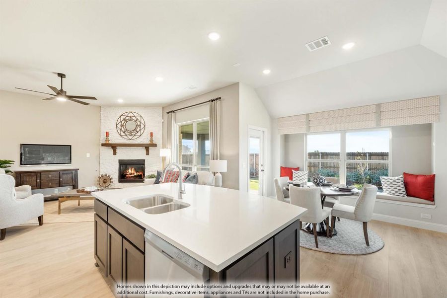 Open-concept kitchen with dark island, white countertop, and views of dining nook and living room with stone fireplace Open-concept kitchen with dark island, white countertop, and views of dining nook and living room with stone fireplace