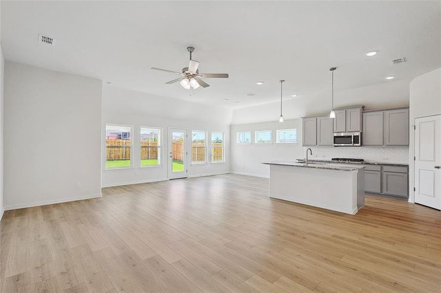 Kitchen with gray cabinets, ceiling fan, light hardwood / wood-style floors, and a healthy amount of sunlight