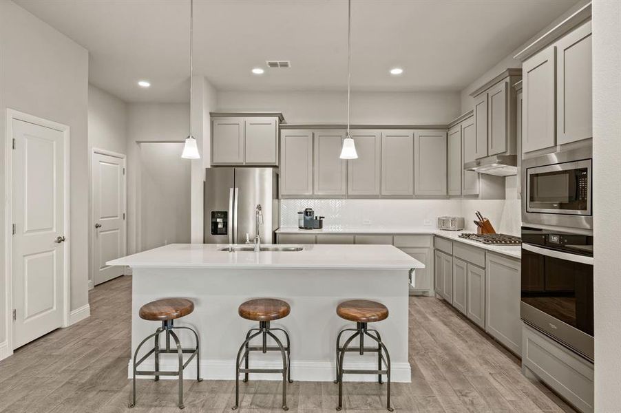 Spacious kitchen with modern finishes, including stainless steel wall oven and microwave combo, designer backsplash, and extensive storage.