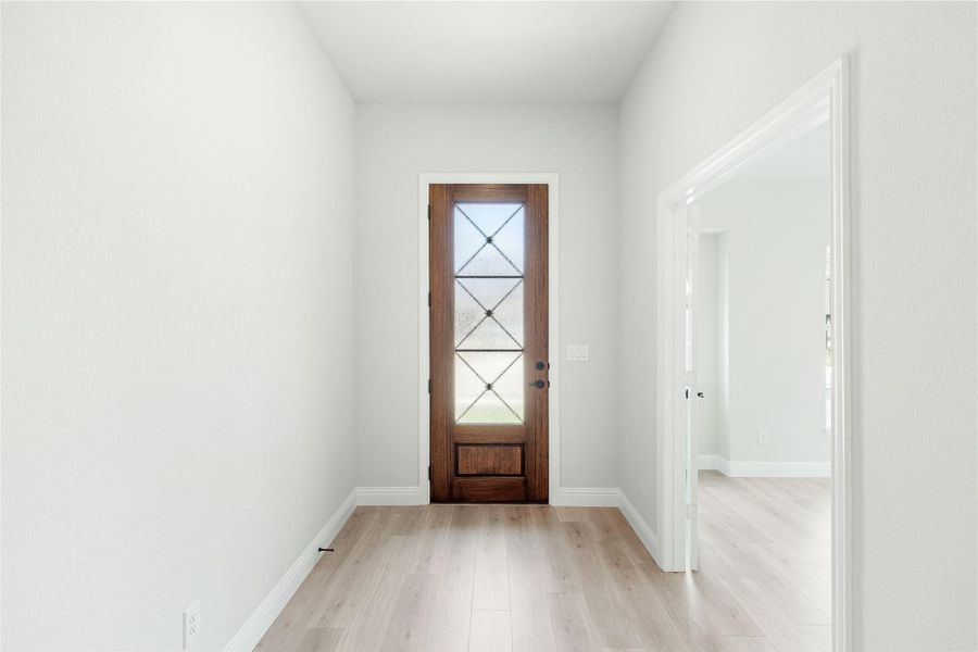 Entryway with wood front door featuring diamond glass panels and light hardwood floors