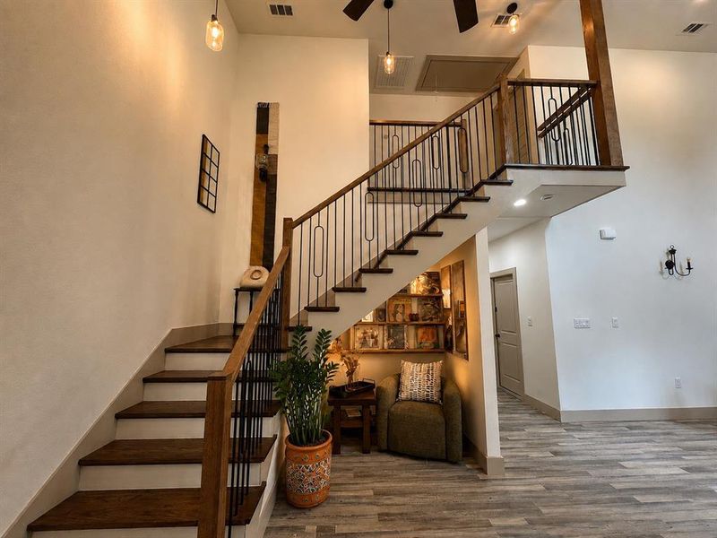 Grand staircase featuring wood-finish treads and risers, wrought iron balusters, and a wood-finish handrail