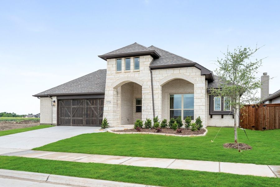 Single-story home with cream stone exterior, arched entryway, two-car garage, and manicured front lawn Single-story home with cream stone exterior, arched entryway, two-car garage, and manicured front lawn