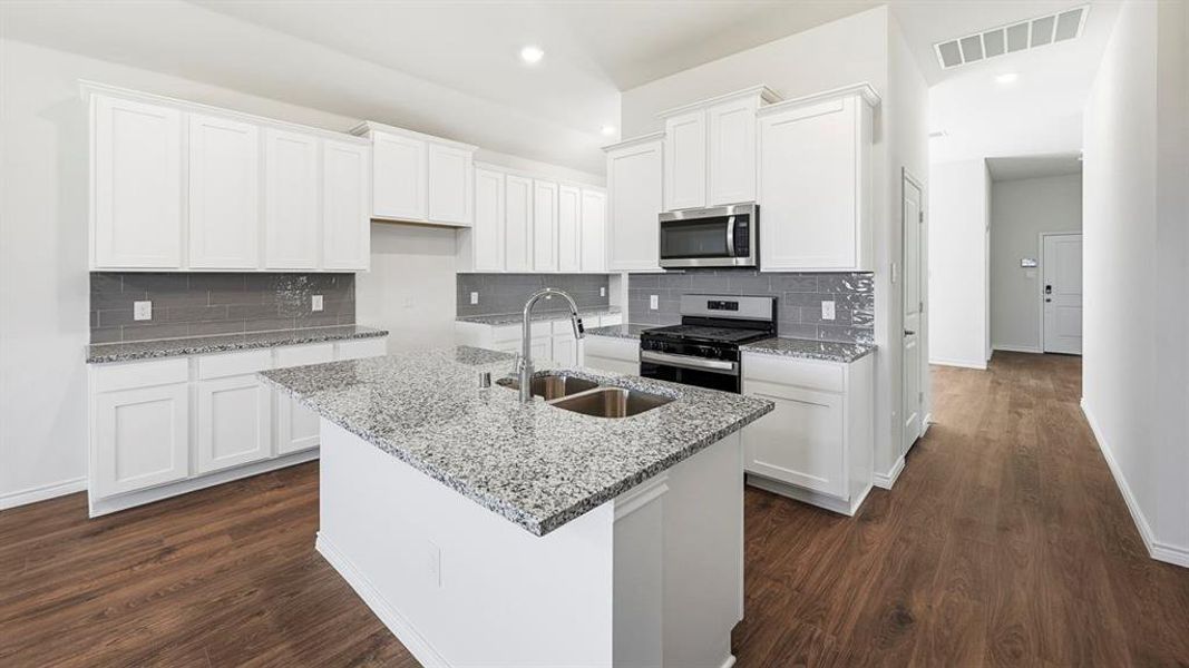 Kitchen with tasteful backsplash, white cabinets, light stone counters, stainless steel appliances, and recessed lighting