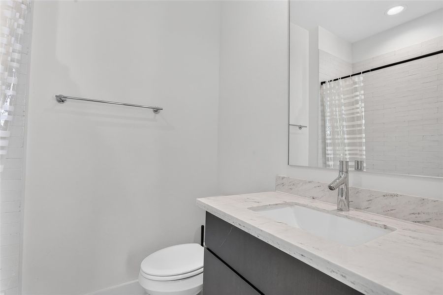 A refined bathroom featuring a contemporary vanity with a gleaming countertop and modern fixtures.