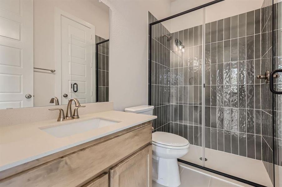 Bathroom with vanity, toilet, tile patterned floors, and an enclosed shower