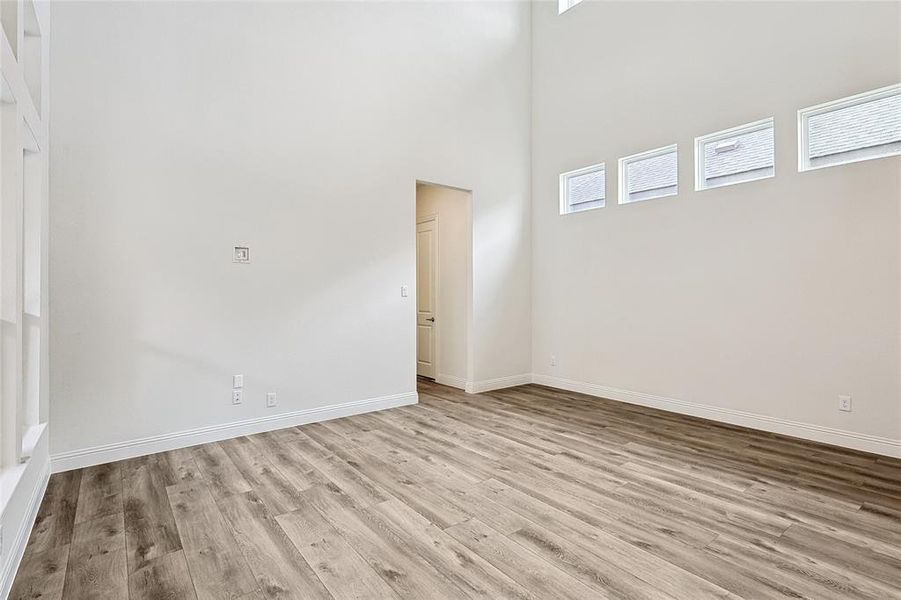 Empty room with a high ceiling and light hardwood / wood-style floors