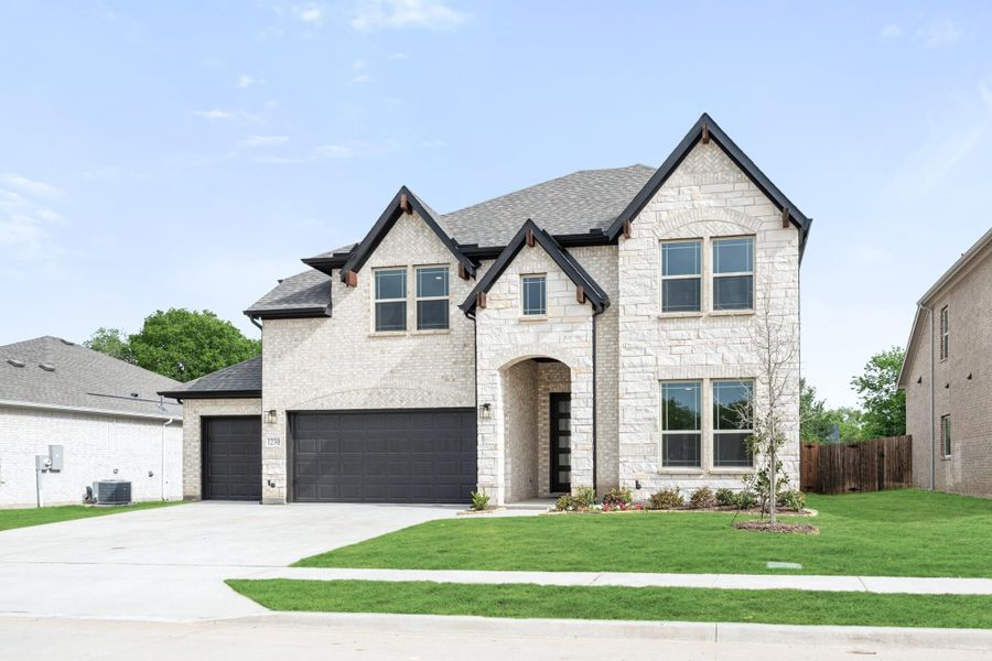 Two-story home with light stone exterior, dark roof, three-car garage, and manicured front lawn