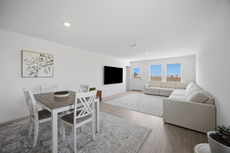 Smooth luxury vinyl floors flow seamlessly through this open-concept layout under a recessed-lit ceiling.