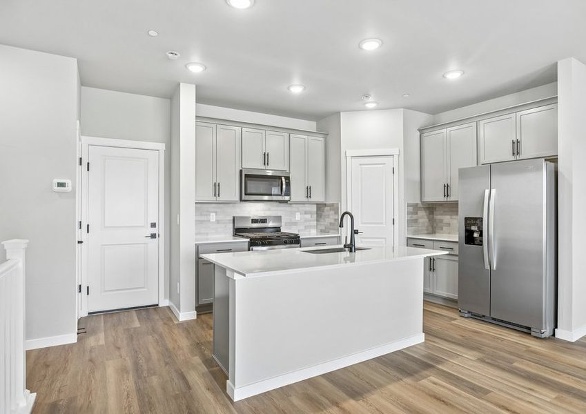 The kitchen has stainless steel appliances and plank flooring.