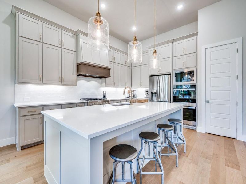 Kitchen featuring stainless steel appliances, light wood-style floors, a sink, backsplash, and a kitchen bar