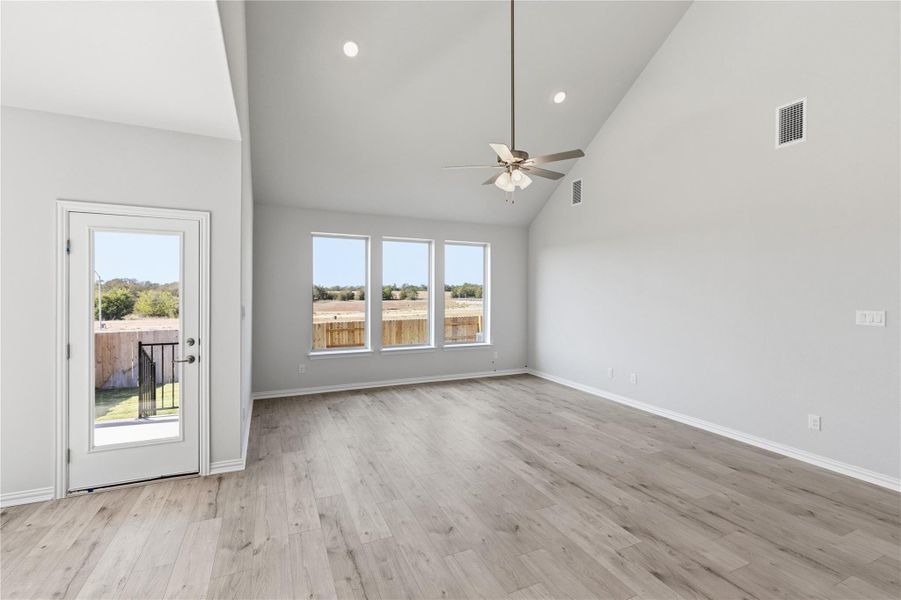 Unfurnished living room with high vaulted ceiling, light wood finished floors, recessed lighting, and a ceiling fan Unfurnished living room with high vaulted ceiling, light wood finished floors, recessed lighting, and a ceiling fan