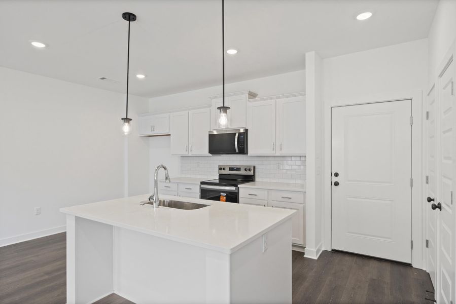 Modern kitchen with white cabinetry and an island featuring a stainless steel sink