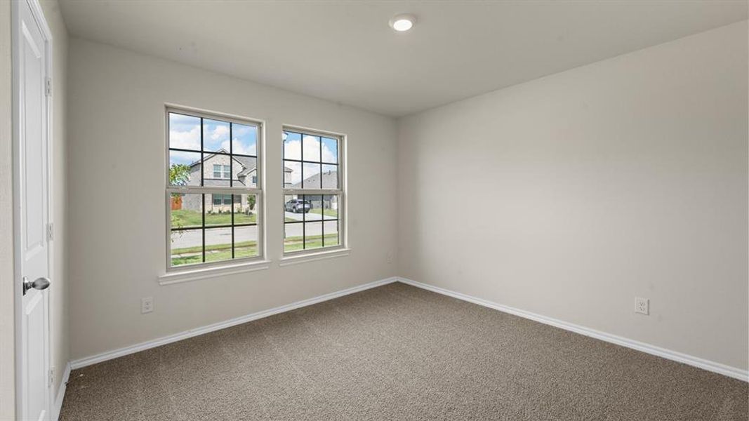 Carpeted interior space featuring two large windows with grid patterns, a white interior door, recessed lighting, and neutral wall paint Carpeted interior space featuring two large windows with grid patterns, a white interior door, recessed lighting, and neutral wall paint