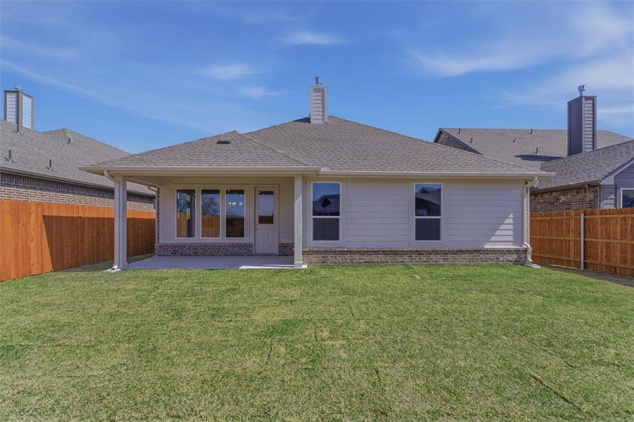 Rear view of house featuring brick siding, a patio, a chimney, a fenced backyard, and a shingled roof