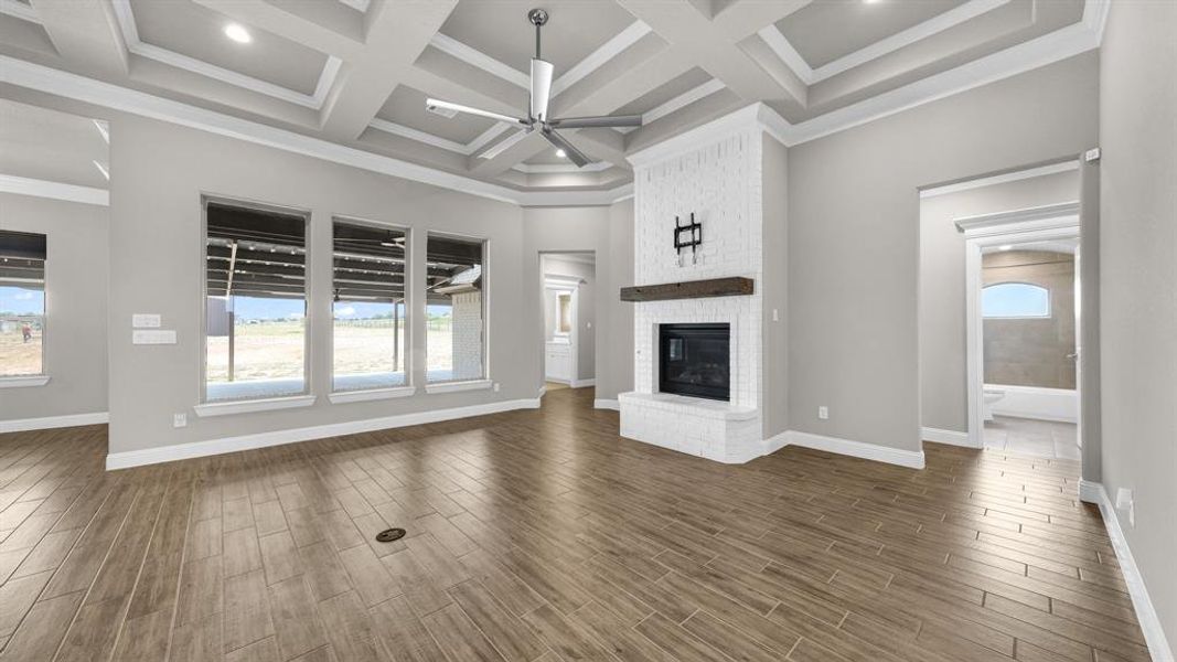 Living room with a fireplace, coffered ceiling, beamed ceiling, ceiling fan, and dark hardwood / wood-style floors