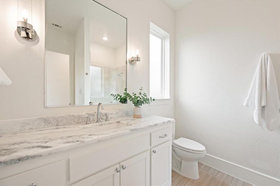 Bathroom featuring plenty of natural light, vanity, tile patterned flooring, and toilet