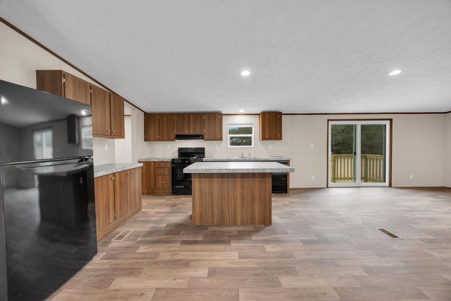 Kitchen featuring black appliances, light countertops, recessed lighting, a center island, and light wood-style flooring