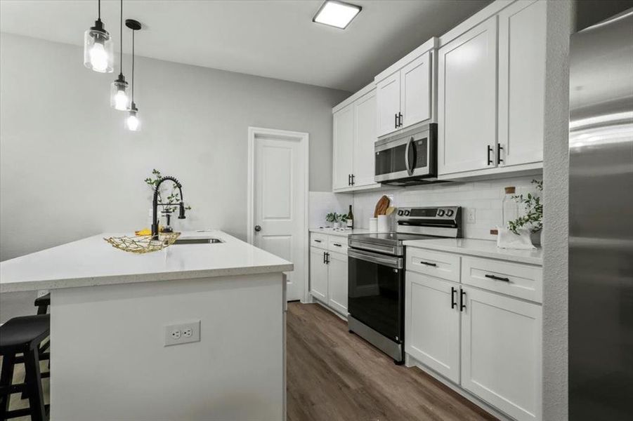 Kitchen with white cabinetry, sink, tasteful backsplash, a center island with sink, and appliances with stainless steel finishes