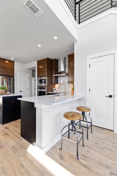 Kitchen with a breakfast bar, a peninsula, stainless steel appliances, modern cabinets, and recessed lighting