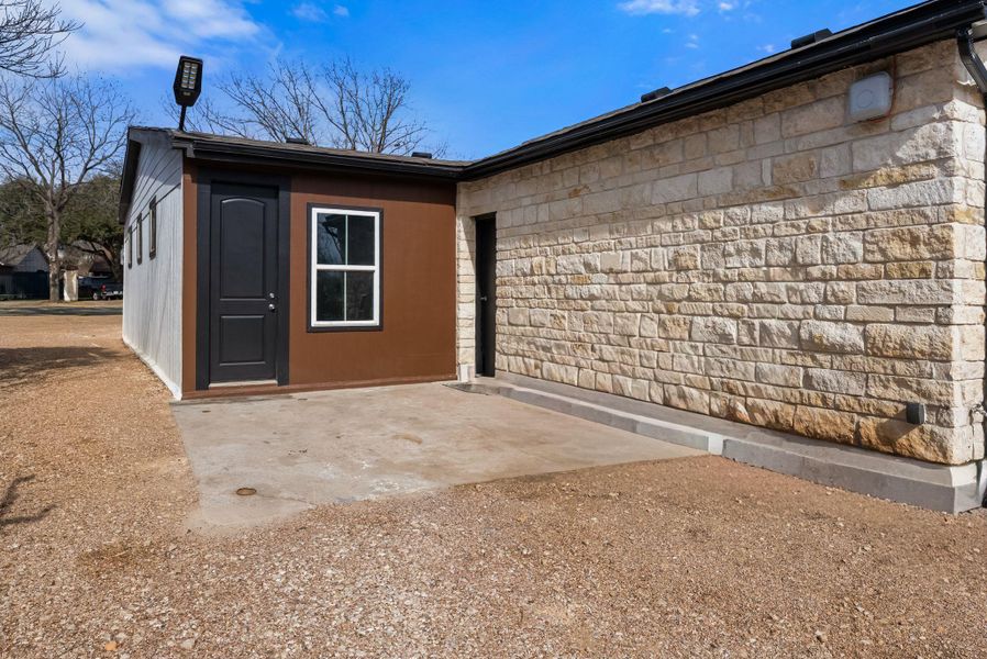 Rear view of house with a patio area and stone siding