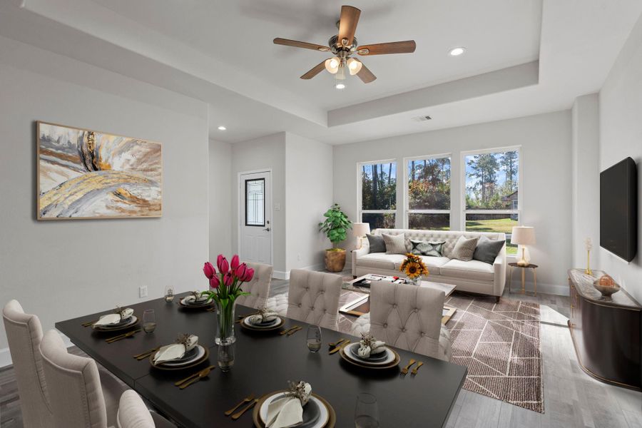 Virtually Staged: This dining and living room area offers a bright, open layout designed for both comfort and style. Large windows along the back wall fill the space with natural light and provide serene views of the wooded surroundings.