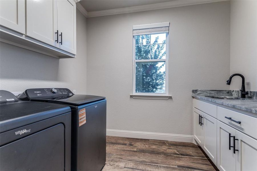 Laundry area with independent washer and dryer, crown molding, dark wood finished floors, and cabinet space