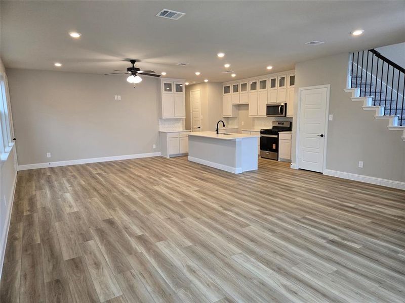 Kitchen featuring open floor plan, white cabinets, recessed lighting, appliances with stainless steel finishes, and light wood-style floors Kitchen featuring open floor plan, white cabinets, recessed lighting, appliances with stainless steel finishes, and light wood-style floors