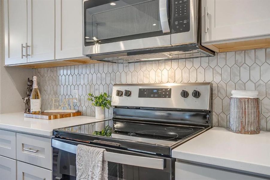 Kitchen featuring white cabinetry, ceiling fan, stainless steel appliances, and decorative backsplash