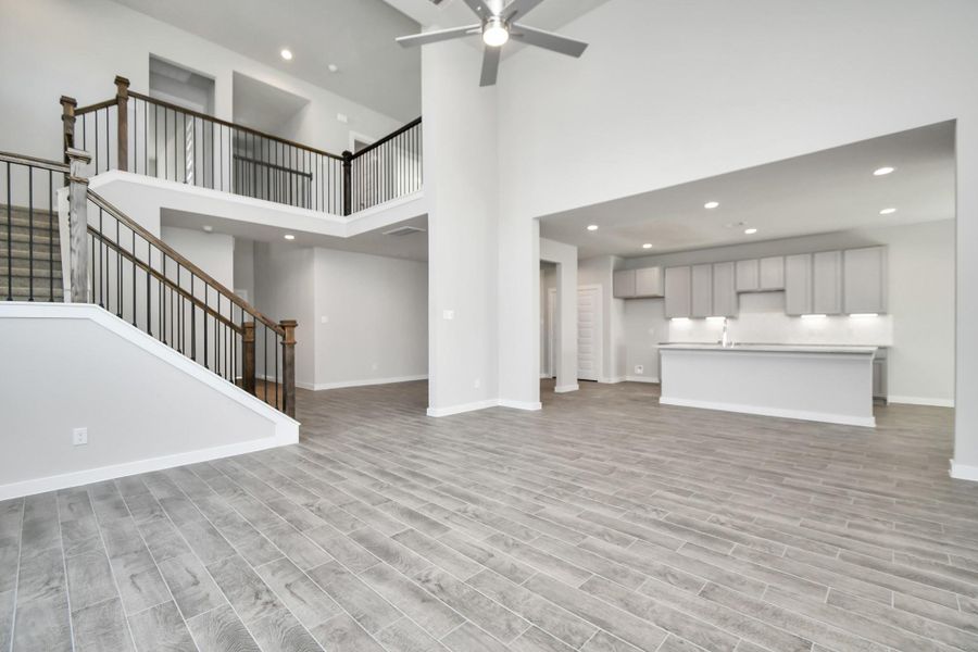 Gather the family and guests together in your lovely living room! Featuring soaring high ceilings, recessed lighting, ceiling fan, custom paint, gorgeous floors, and large windows that provide plenty of natural lighting throughout the day. Sample photo of completed home with similar floor plan. As-built interior colors and selections may vary.