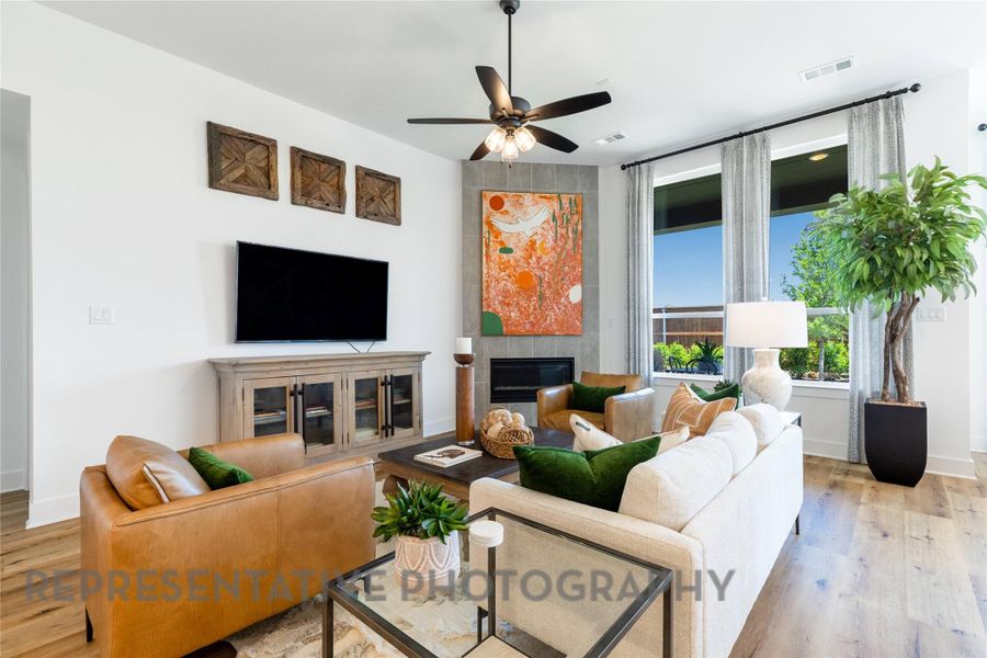 Living area featuring a fireplace, light wood-style floors, and ceiling fan Living area featuring a fireplace, light wood-style floors, and ceiling fan