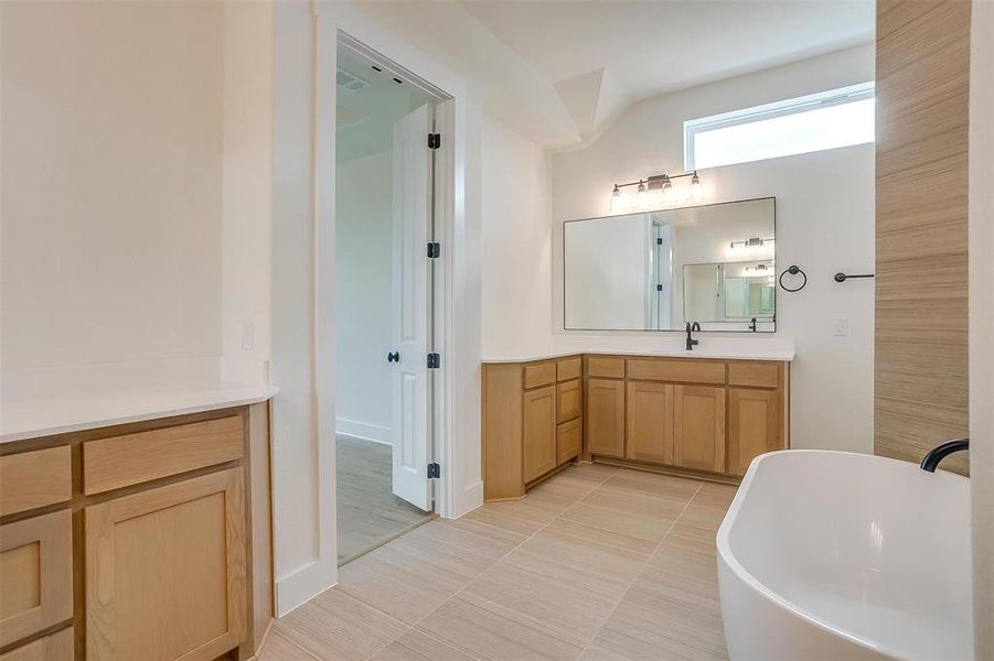 Bathroom with vanity, tile patterned flooring, and a bathtub