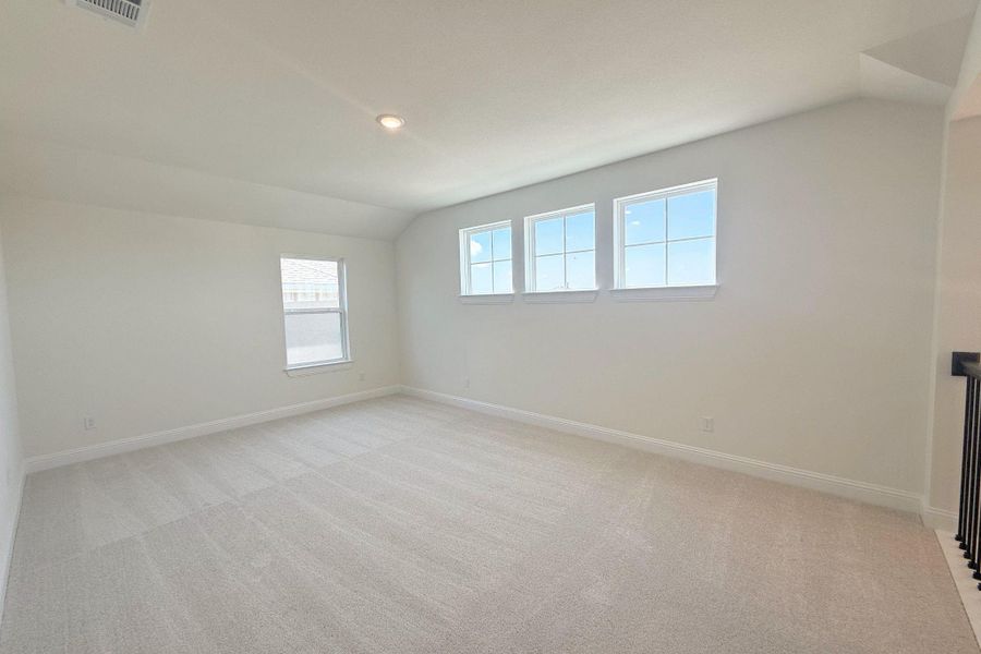 Spacious room featuring light-colored carpeting, white baseboards, and bright white walls