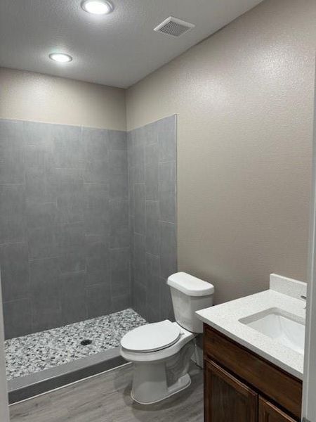 Full bathroom with visible vents, a shower stall, toilet, wood finished floors, and vanity