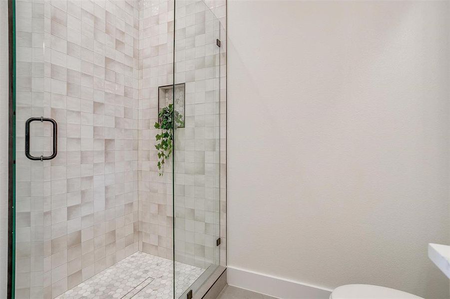 Bathroom featuring a stall shower, toilet, and baseboards