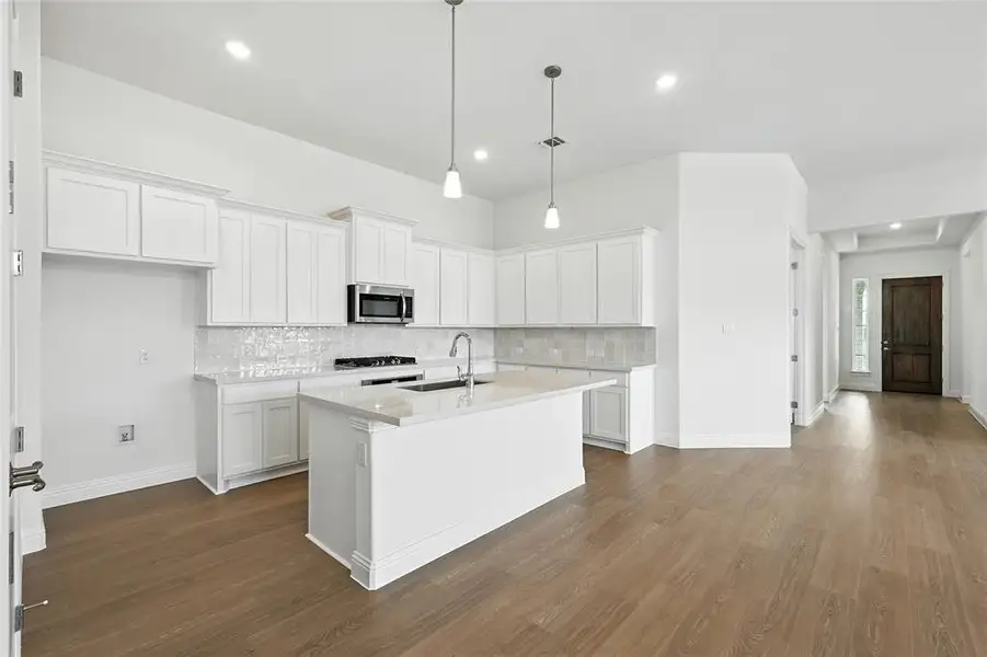 Kitchen featuring white cabinets, decorative backsplash, pendant lighting, dark wood-type flooring, and recessed lighting