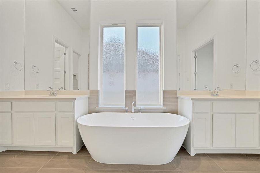 Bathroom featuring tile flooring, a bathtub, walk-in shower and two vanities