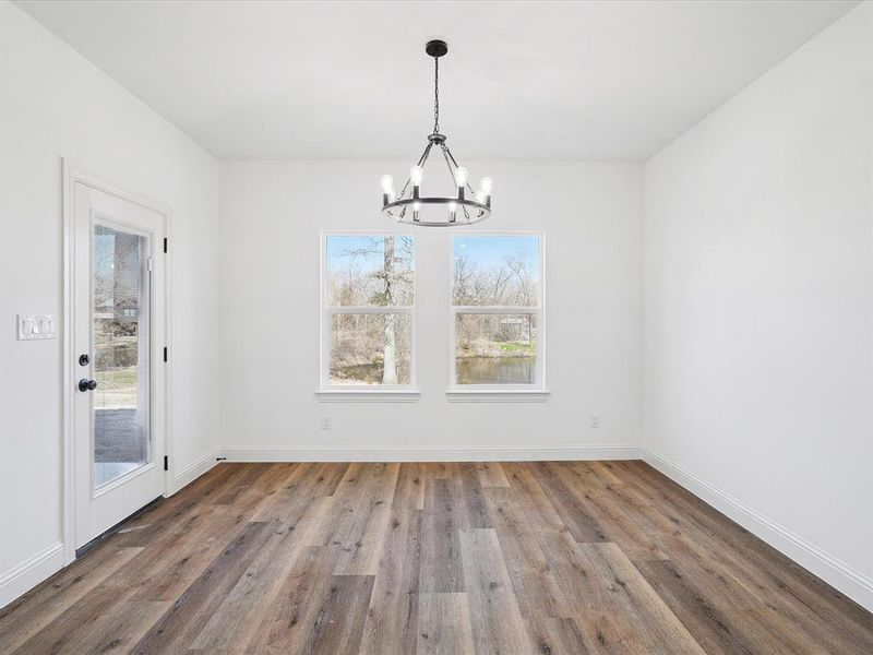 Unfurnished dining area featuring wood finished floors and a chandelier