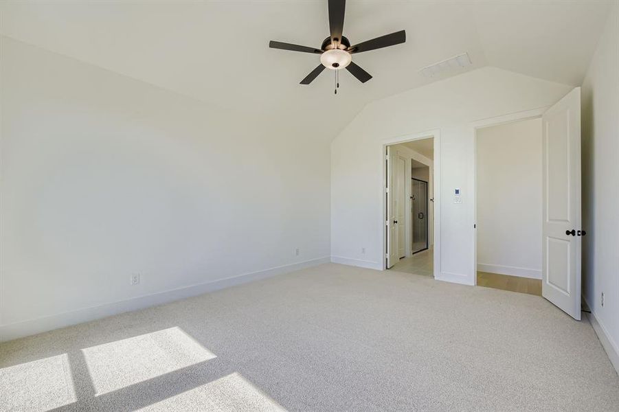 Unfurnished bedroom with light carpet, lofted ceiling, and a ceiling fan Unfurnished bedroom with light carpet, lofted ceiling, and a ceiling fan