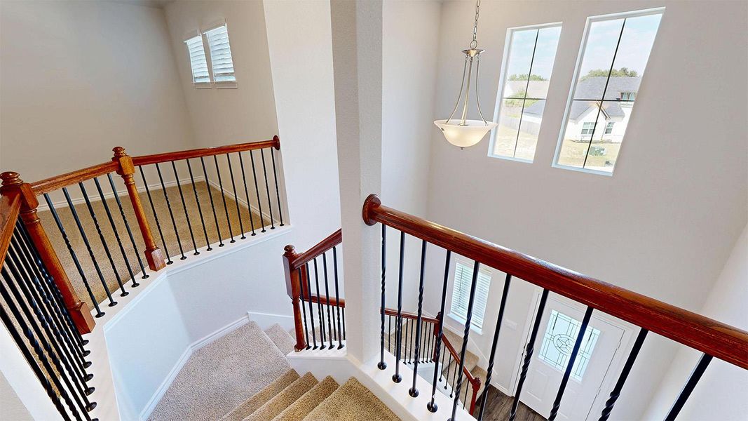 The property features a staircase with carpeted treads, dark wood banisters, and black metal balusters