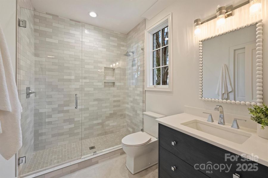 Ensuite bathroom to first bedroom, featuring quartz countertops and designer tile selections.