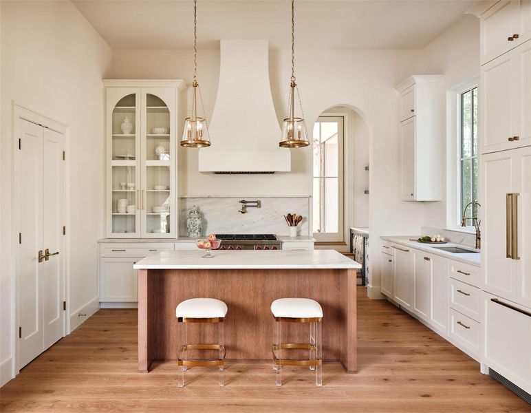 Large kitchen island. Paneled appliances and range hood treated with venetian plaster. Designer fixtures and hardware.