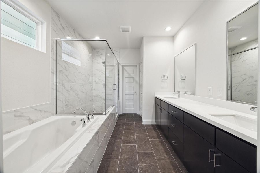 This luxurious primary bathroom features a sleek, modern design. The double vanity offers ample storage and counter space, while the oversized soaking tub invites relaxation.