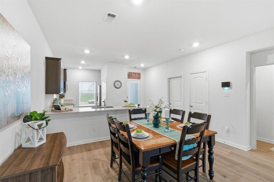 The dining area features light wood flooring, an open-concept layout, and recessed lighting