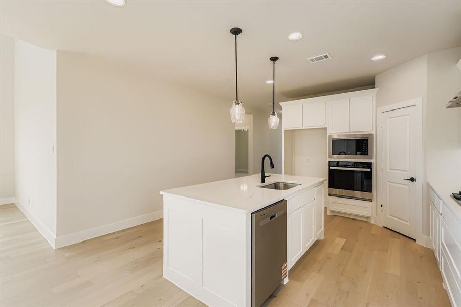 Kitchen with recessed lighting, appliances with stainless steel finishes, light wood-type flooring, white cabinets, and pendant lighting