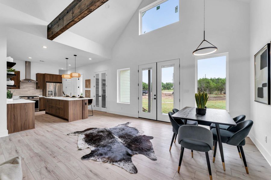 Dining space with french doors, plenty of natural light, light wood-style floors, high vaulted ceiling, and beam ceiling