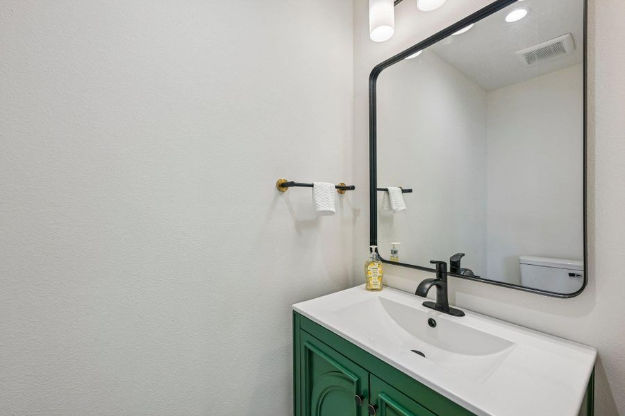 Modern half bath with vanity with a bold green cabinet and contemporary fixtures. Modern half bath with vanity with a bold green cabinet and contemporary fixtures.