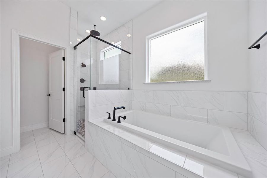Full bath with a shower stall, a bath, and marble look tiles