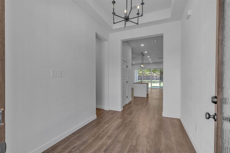 Corridor with hardwood / wood-style flooring and an inviting chandelier