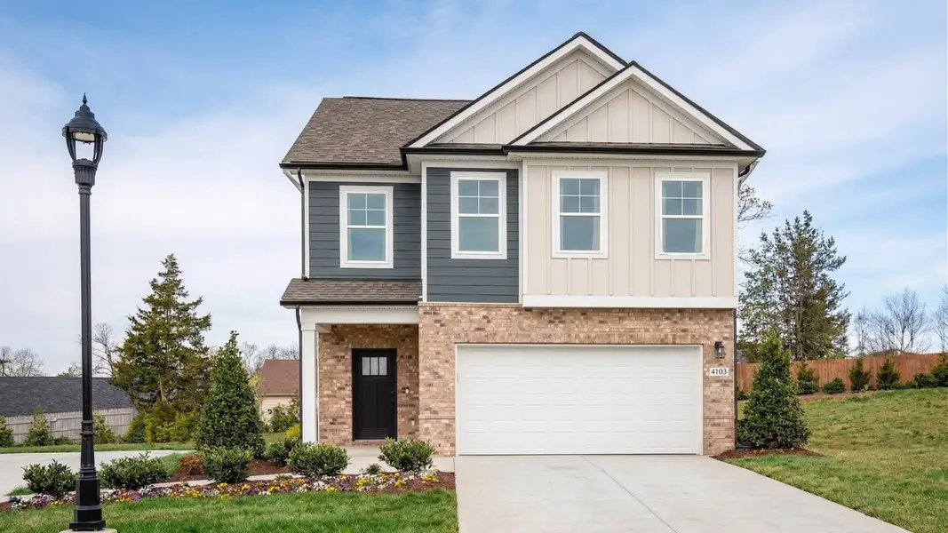 Exterior of home with two-tone siding and brick first floor with attractive landscaping and community lighting