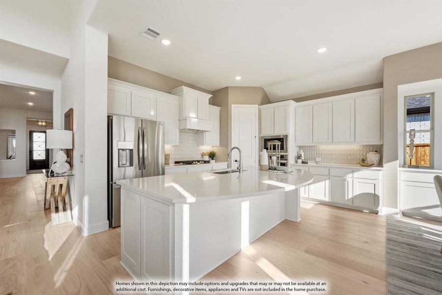 Open kitchen with white cabinets, large center island, stainless steel refrigerator, and light hardwood floors Open kitchen with white cabinets, large center island, stainless steel refrigerator, and light hardwood floors